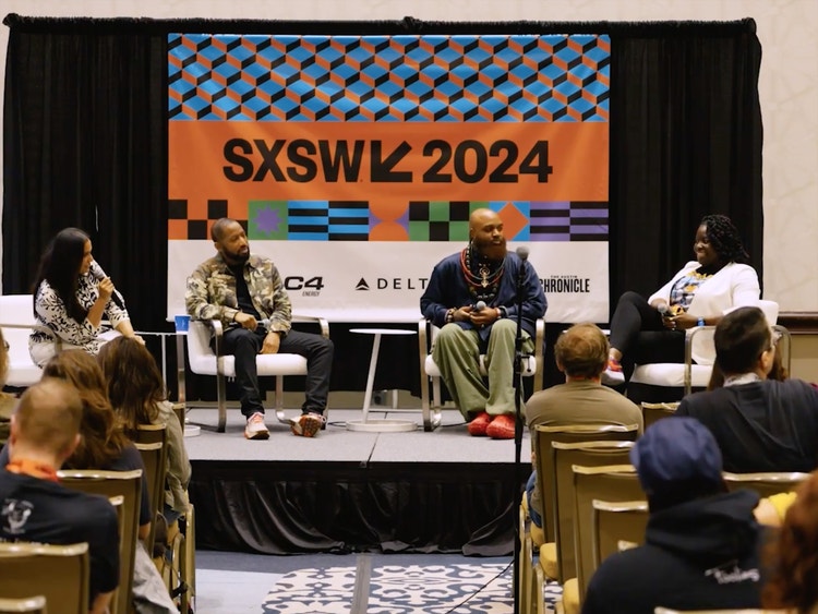 A photograph of (from left) an Indian woman, two Black men, and a Black woman seated on a stage (facing an audience and the camera) under a banner that reads SXSW 2024. The audience is in the foreground facing the stage with the backs of their heads toward the camera.