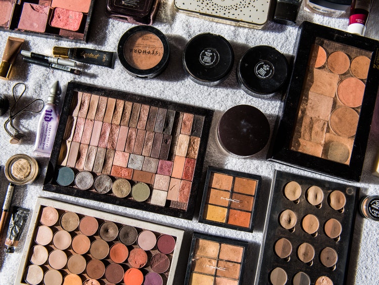 A photograph of various containers and types of makeup artfully arranged on a table.