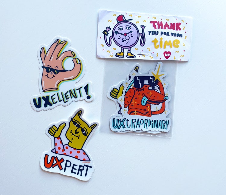 Three stickers arranged on a whiteboard. Clockwise from top left: 1. a hand giving the OK sign and the caption UXellent! 2. A clock and the caption Thank you for your time 3. a dog with sunglasses and the caption UXtraordinary 4. a cat giving a thumbs up and the caption UXpert.