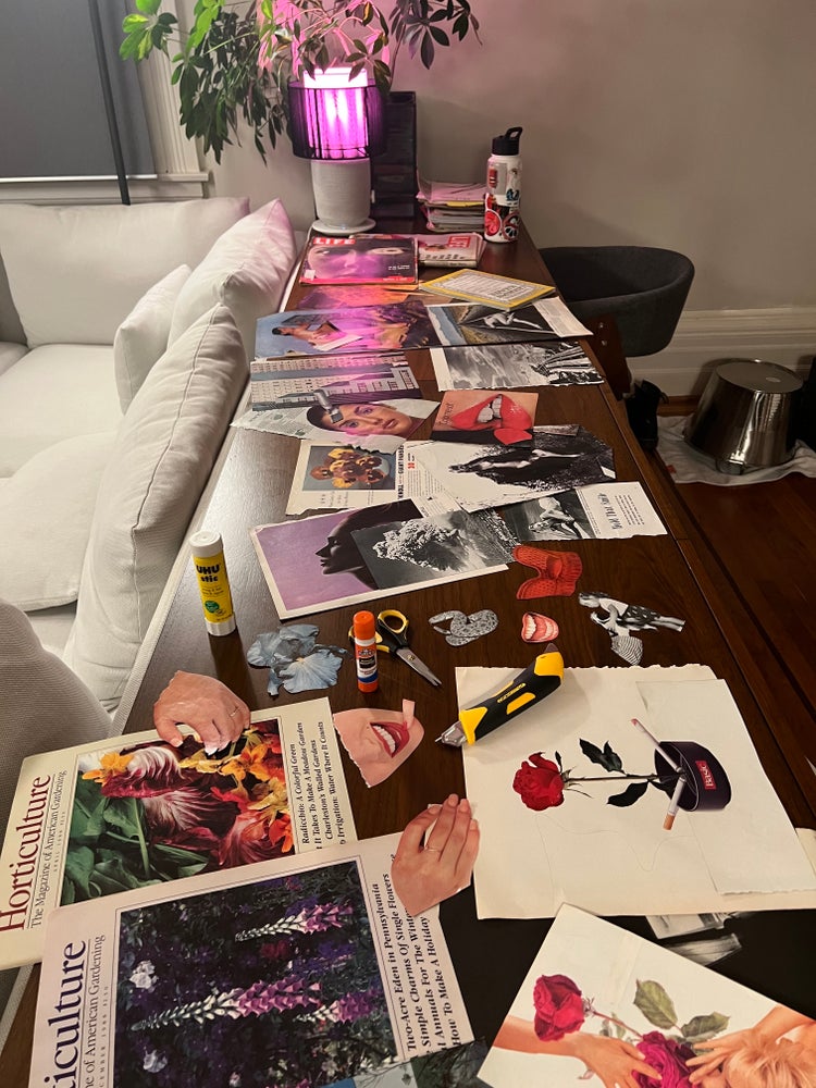 A couch backs up to a long table strewn with magazines, cut-out images, glue sticks, and scissors.